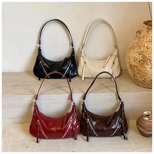Detail of four colorful glossy patent leather crescent bags with silver zippers on stone steps