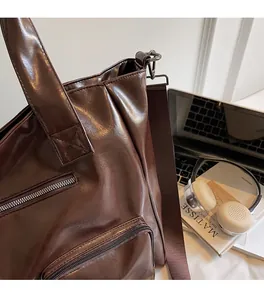Detail of dark brown faux leather tote bag with functional zipper and adjustable strap