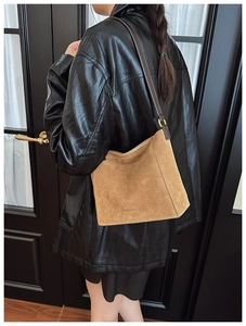 Detail of camel suede tote bag with brand logo and deep brown shoulder strap shown on model