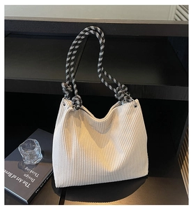 Close-up of beige corduroy tote with woven black and white checkered rope handles