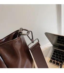 Detailed close-up of dark brown glossy leather bag with gunmetal D-ring and lobster clasp