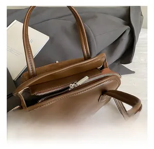 Detail of dark brown leather handbag with silver zipper and suede patchwork texture