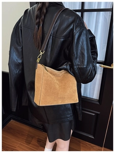Detail of brown suede hobo bag featuring gold metal hooks and luxury brand logo