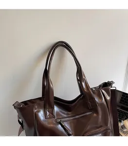 Close-up of vintage brown leather tote bag with functional zippers and wide shoulder strap