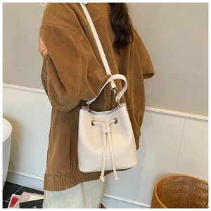 Detail of cream drawstring bucket bag showing lychee pattern leather and gold hardware