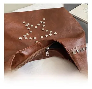 Detail of brown leather bag with silver star rivets and smooth metal zipper closure