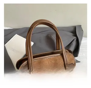 Detailed close-up of retro brown suede handbag with metal clasp and double handles