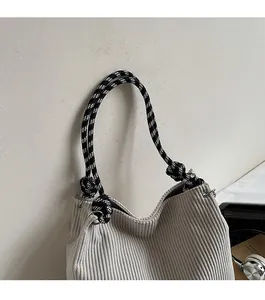 Detail of light grey corduroy tote bag with black and white checkered rope handles