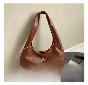Close-up of brown leather shoulder bag with silver rivet star pattern and wide handle