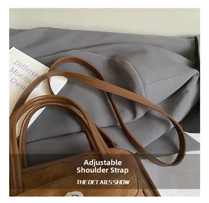 Detail view of the adjustable shoulder strap on a brown suede texture handbag
