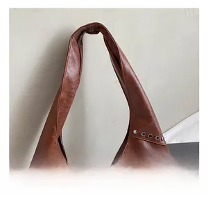 Close-up of brown leather shoulder bag featuring vintage texture and silver metal rivets