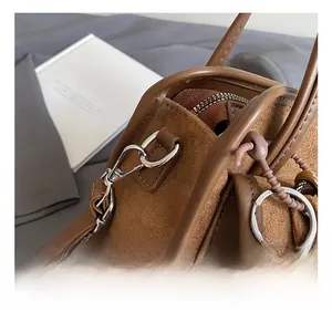 Close-up of premium metal hook and brown woven ball charm on a vintage satchel