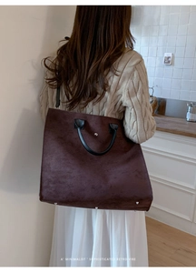 Dettaglio della borsa tote in pelle scamosciata marrone con manici neri e rivetti
