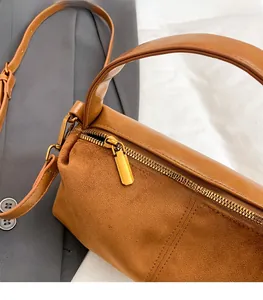 Close-up of brown Boston bag showing gold zipper hardware and contrast leather textures