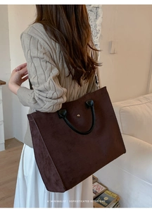 Dettaglio della borsa tote in finto camoscio marrone scuro con manici neri e borchia