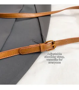 Close-up of brown matte leather adjustable shoulder strap with vintage gold buckle