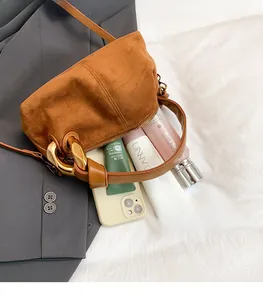 Detailed top view of brown suede cylinder bag showing interior space for phone and makeup