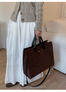 Dettaglio della borsa tote in pelle scamosciata marrone con manici neri e fibbie dorate