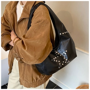 Detail of black leather hobo bag featuring silver rivets and wide shoulder strap