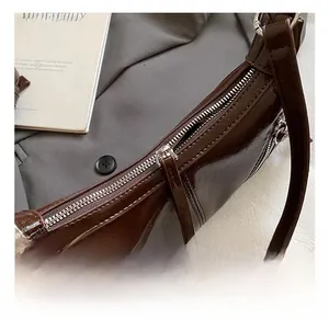 Detailed close-up of the silver hardware and dark brown patent leather on the shoulder bag