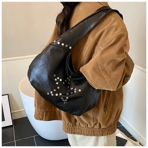 Detail of silver rivets forming a star pattern on a black glossy leather shoulder bag