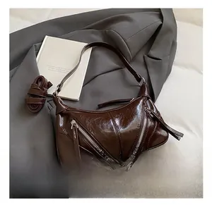 Macro detail of dark brown glossy hobo bag with metal zippers and long tassel pulls