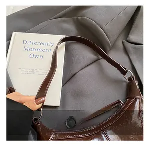 Detailed close-up of a dark brown patent leather hobo bag with polished metal ring handle