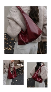 Detailed close-up of dark red glossy tote bag showing sleek crescent shape and wide strap