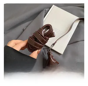 Detail showing high-gloss brown leather texture and adjustable shoulder strap buckle