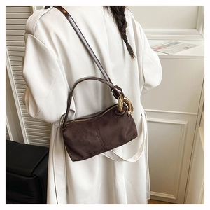 Close-up of brown suede Boston bag with matte texture and chunky gold chain handle