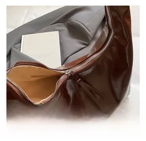 Close-up of brown polished leather tote interior with zipper detail and silver hardware