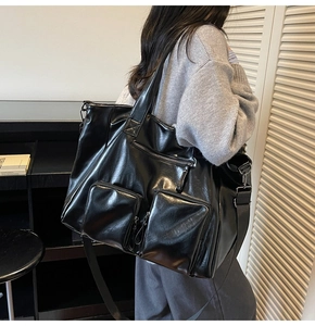 Model wearing a large black vintage washed PU leather tote bag with functional pockets