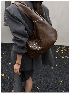 Close-up of vintage brown shoulder bag featuring silver rivet studs and textured PU leather