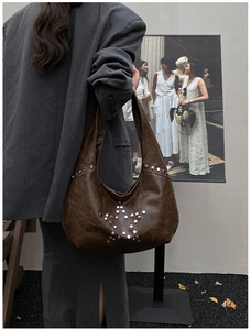 Detail of vintage brown leather shoulder bag with silver rivet star pattern and rivets