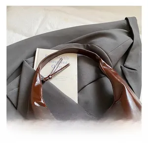 Close-up of a vintage dark brown patent leather tote bag with smooth glossy finish
