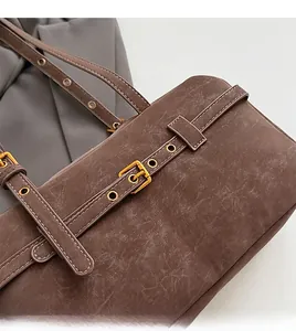 Close-up of vintage brown cracked leather and golden metal buckle on a Boston bag