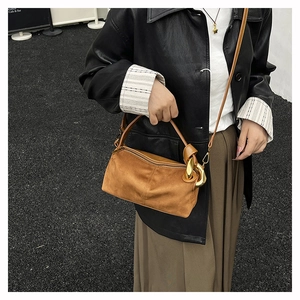 Close-up of caramel suede barrel bag featuring chunky gold chain link hardware