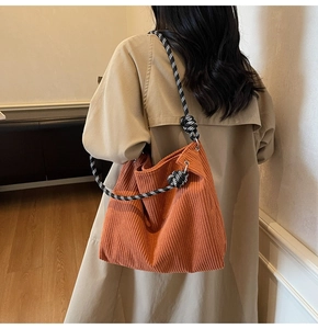Detail of orange corduroy tote bag with black and white checkered braided rope strap