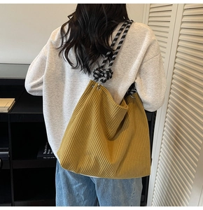 Detail view of mustard yellow corduroy tote bag with stylish plaid braided shoulder strap