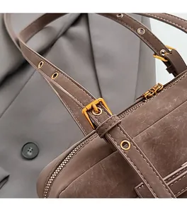 Close-up of premium gold hardware and leather stitching on a taupe tote shoulder bag