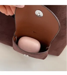 Detail of a brown suede small storage pouch with metal snap button and interior pocket