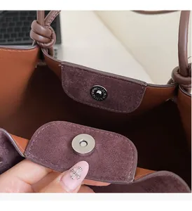 Macro detail of magnetic gold hardware and lychee grain leather on brown tote bag