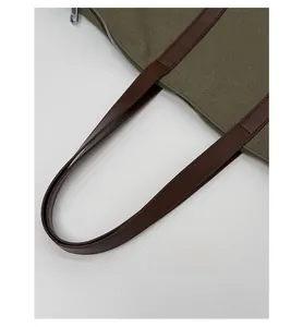 Detail of durable canvas tote bag with brown leather handles and neat stitching
