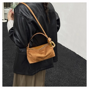 Detailed close-up of brown suede boston bag featuring decorative gold metal ring buckle