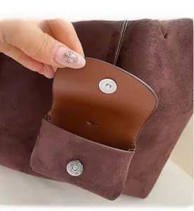 Detail of burgundy suede tote with magnetic snap and mini removable brown leather pouch