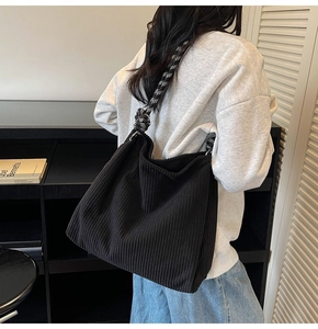 Close-up of black corduroy tote bag with stylish black and white woven rope strap
