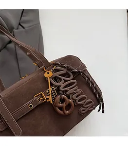 Detail of dark brown leather tote bag with vintage gold hardware and pretzel charm
