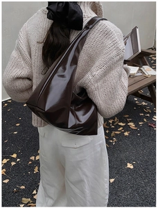 Close-up of a glossy dark brown leather shoulder bag with sleek minimalist streamlined design