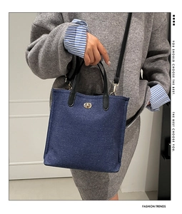 Detail of blue denim crossbody bag with gold oval twist lock and leather handle