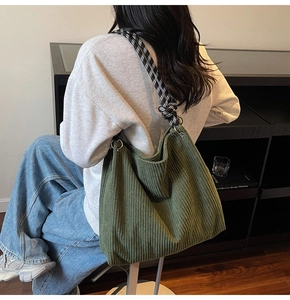 Detail of green corduroy tote bag featuring checkerboard rope strap and textured fabric